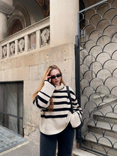 a lady wears a loose fit striped sweater and black pants